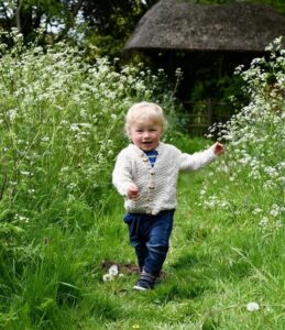 A toddler running through a field with wildflowers