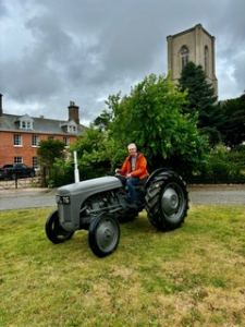 A man on his tractor outside an Anglican church.